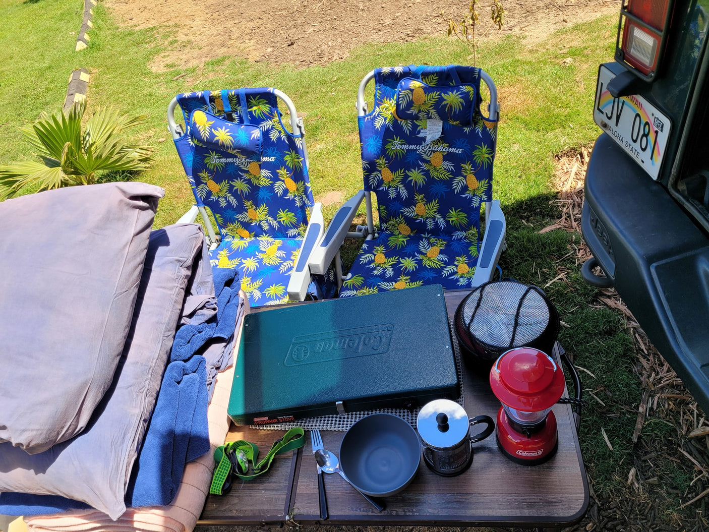RV rental setup: Relax with Tommy Bahama chairs, Coleman gear for camping meals, and cozy bedding outdoors.