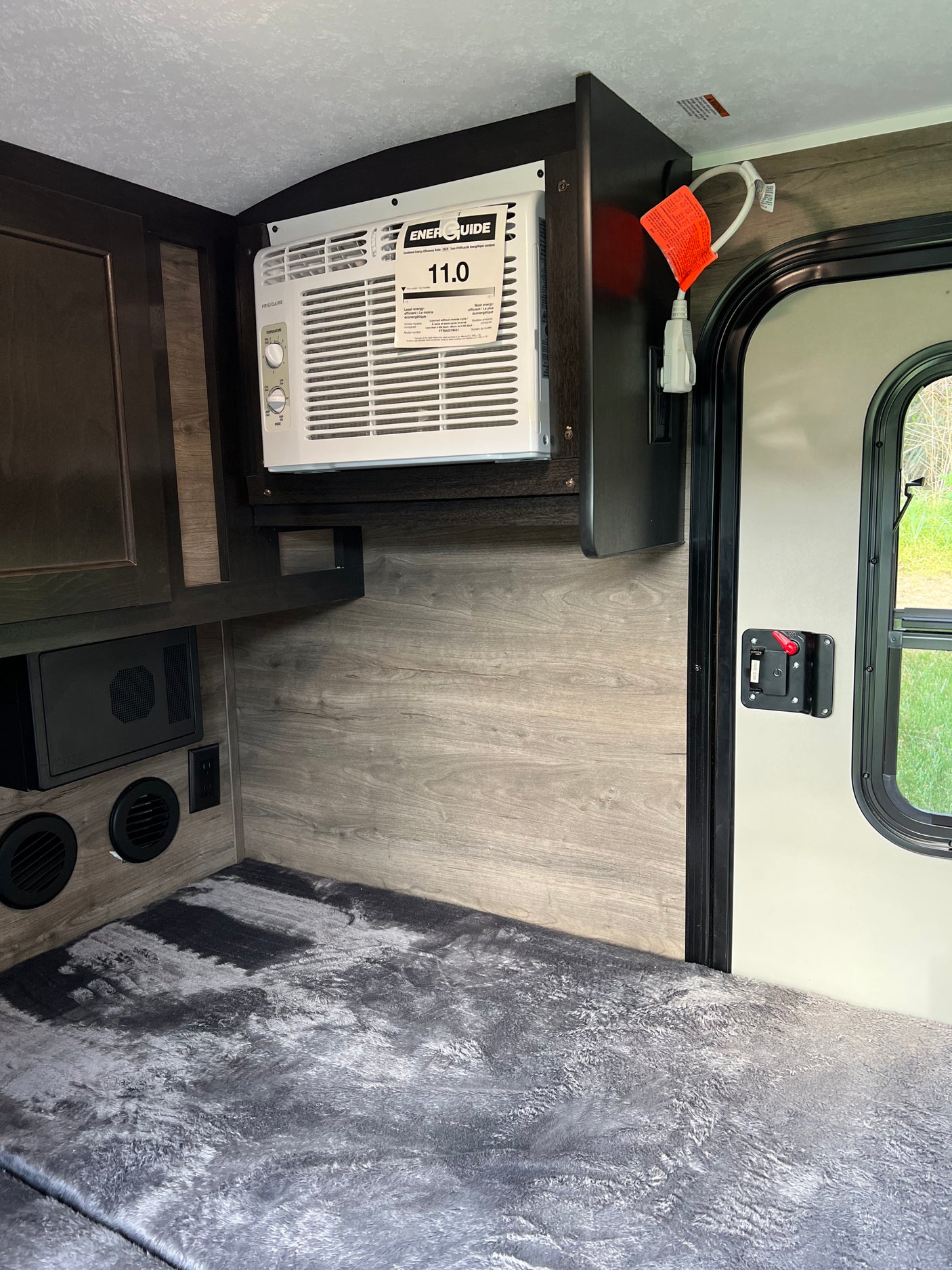Inside an RV rental: a compact living space featuring a wall-mounted AC, comfortable bedding, and practical cabinetry.