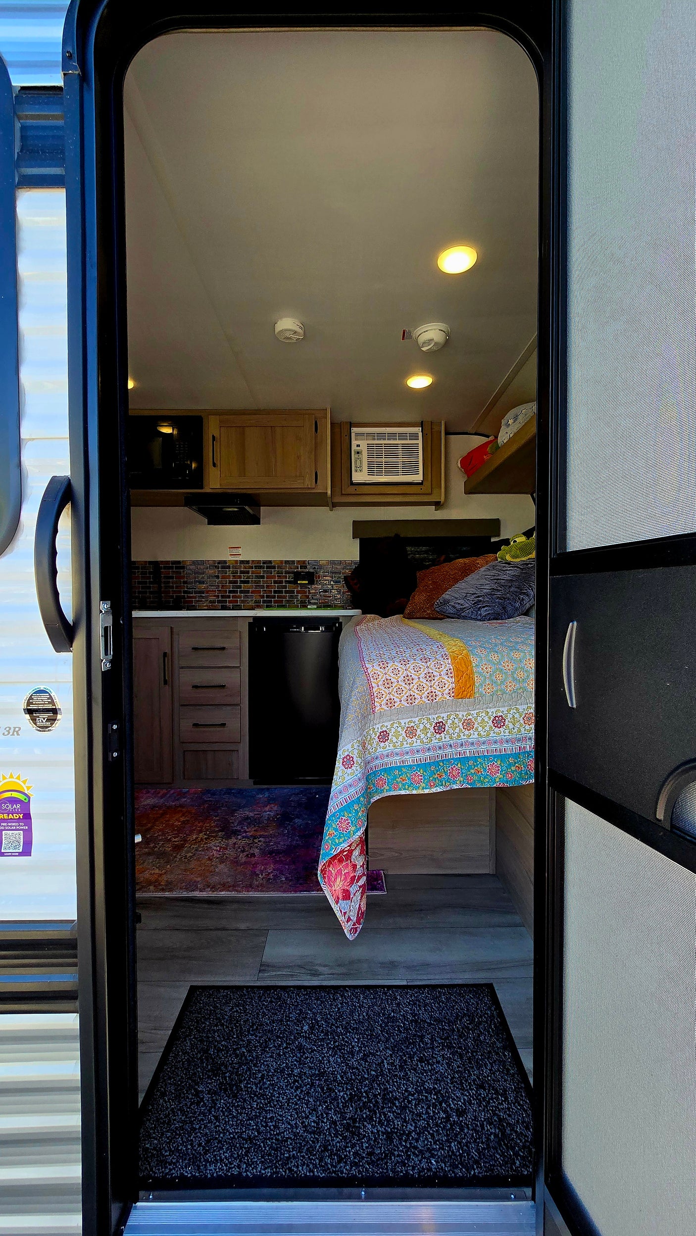 Inside a bright RV rental: compact kitchen, cozy bed, and AC unit. Perfect for comfortable adventures on the road.