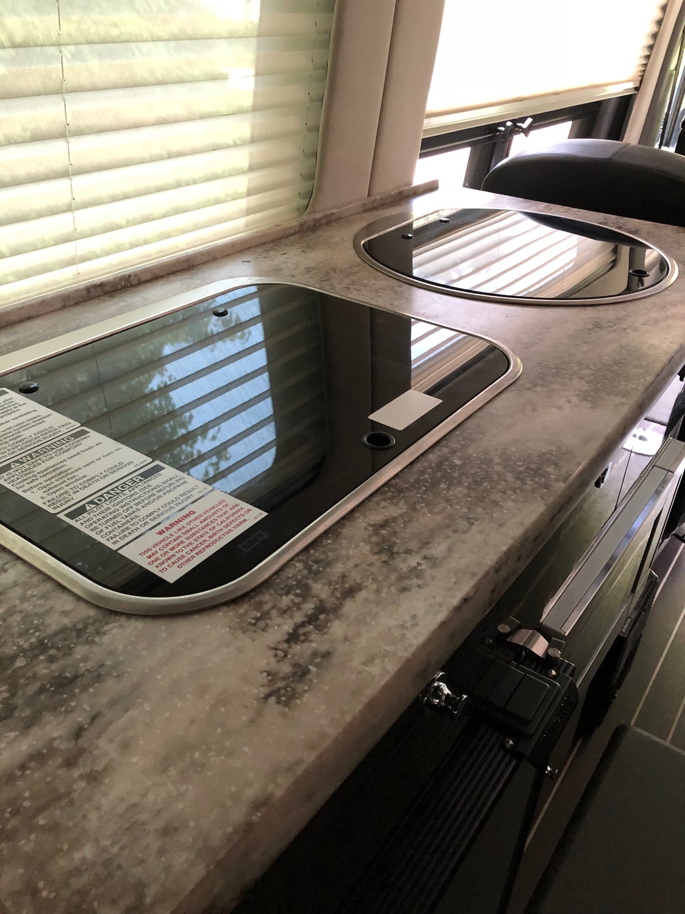 with warning label & decorative pillows.|RV rental interior featuring a large overhead screen & a small sun visor screen