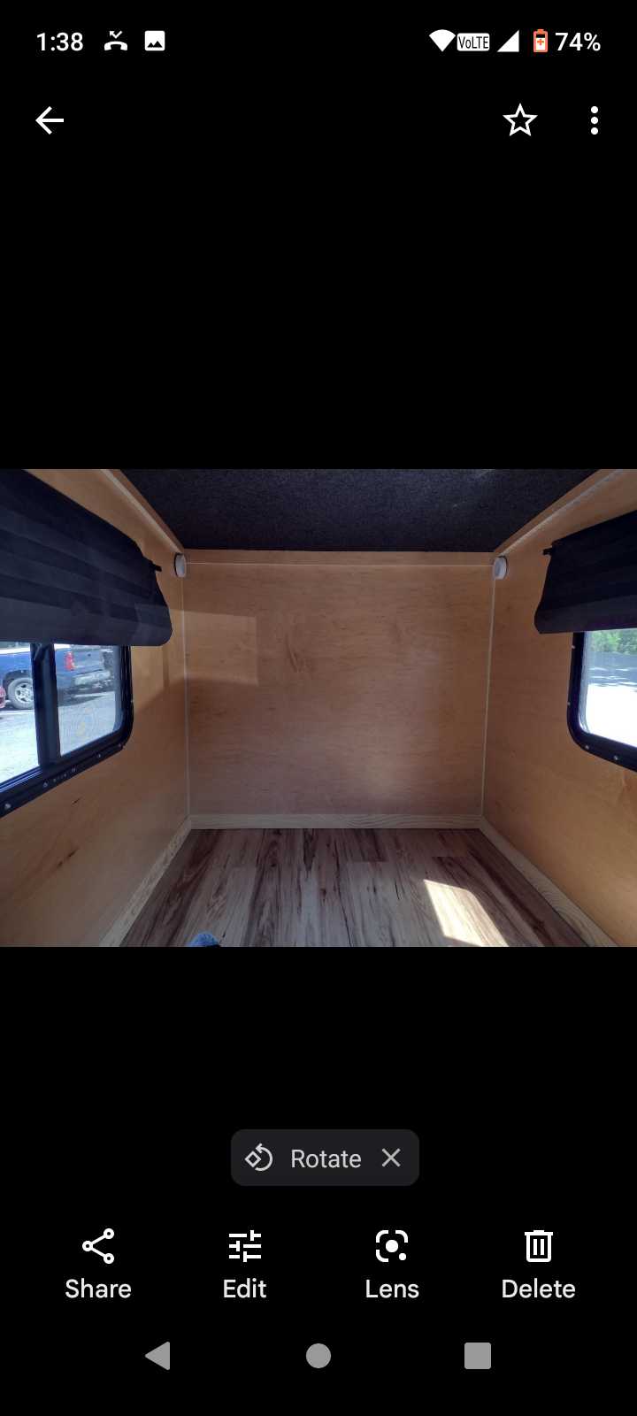 Empty RV rental interior features light wood walls, laminate flooring, and dark ceiling. Ready for your adventure.