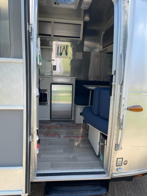Explore this bright rv rental interior: modern kitchen, living area with blue couch, TV, and wood-look floor. — photo 8