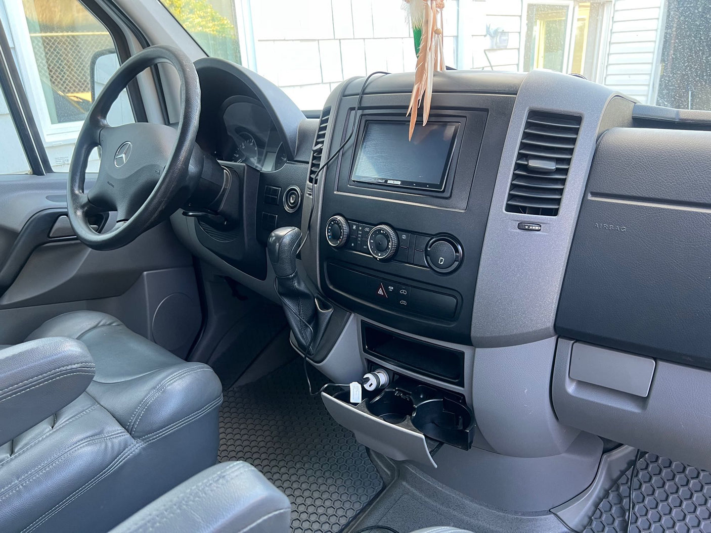 Driver's view of an RV rental: Mercedes-Benz dashboard, steering wheel, infotainment, and gray seating. Clean and functional.
