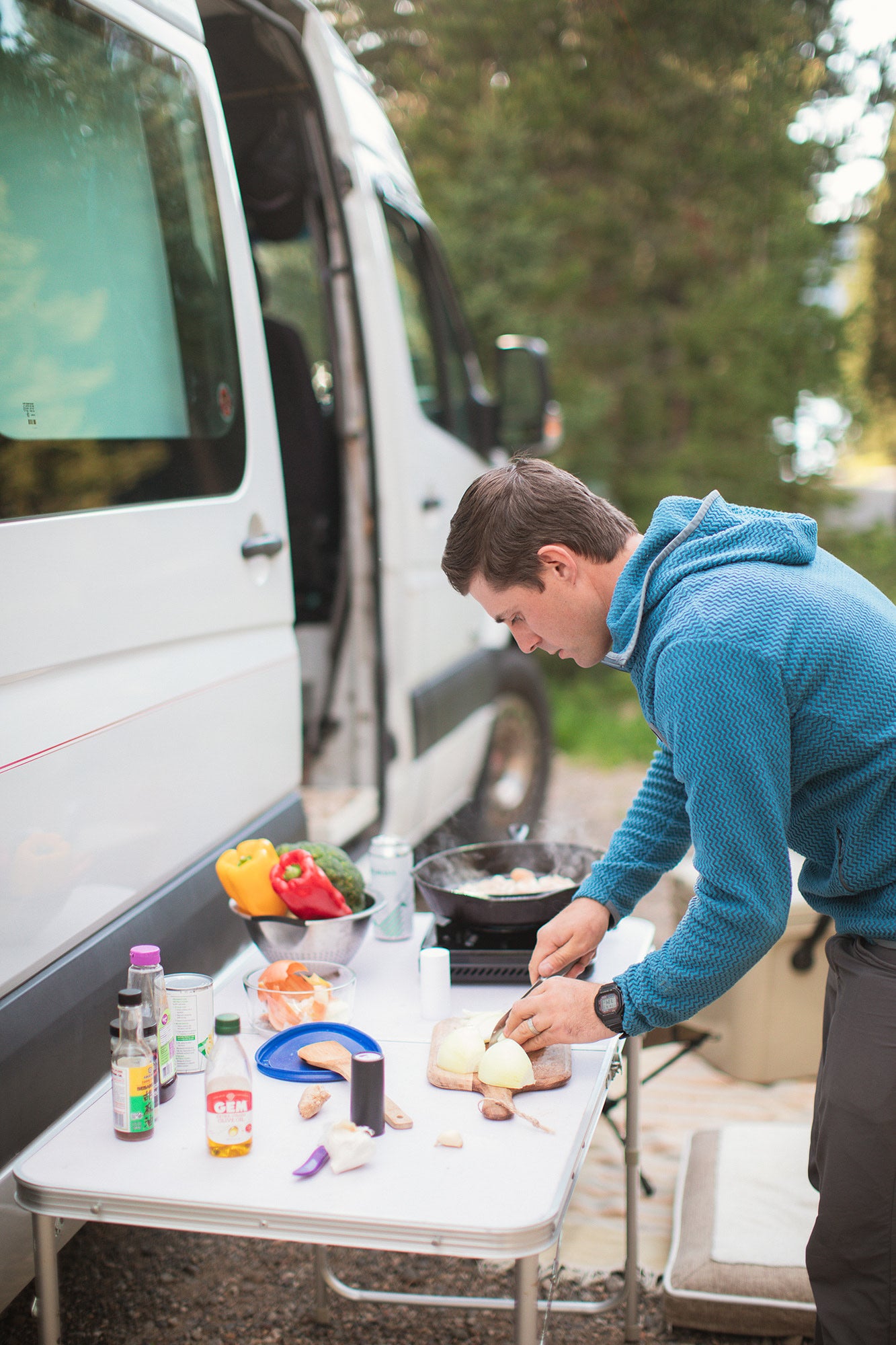 Cooking a fresh meal outdoors with an RV rental. A man preps vegetables by his camper van.