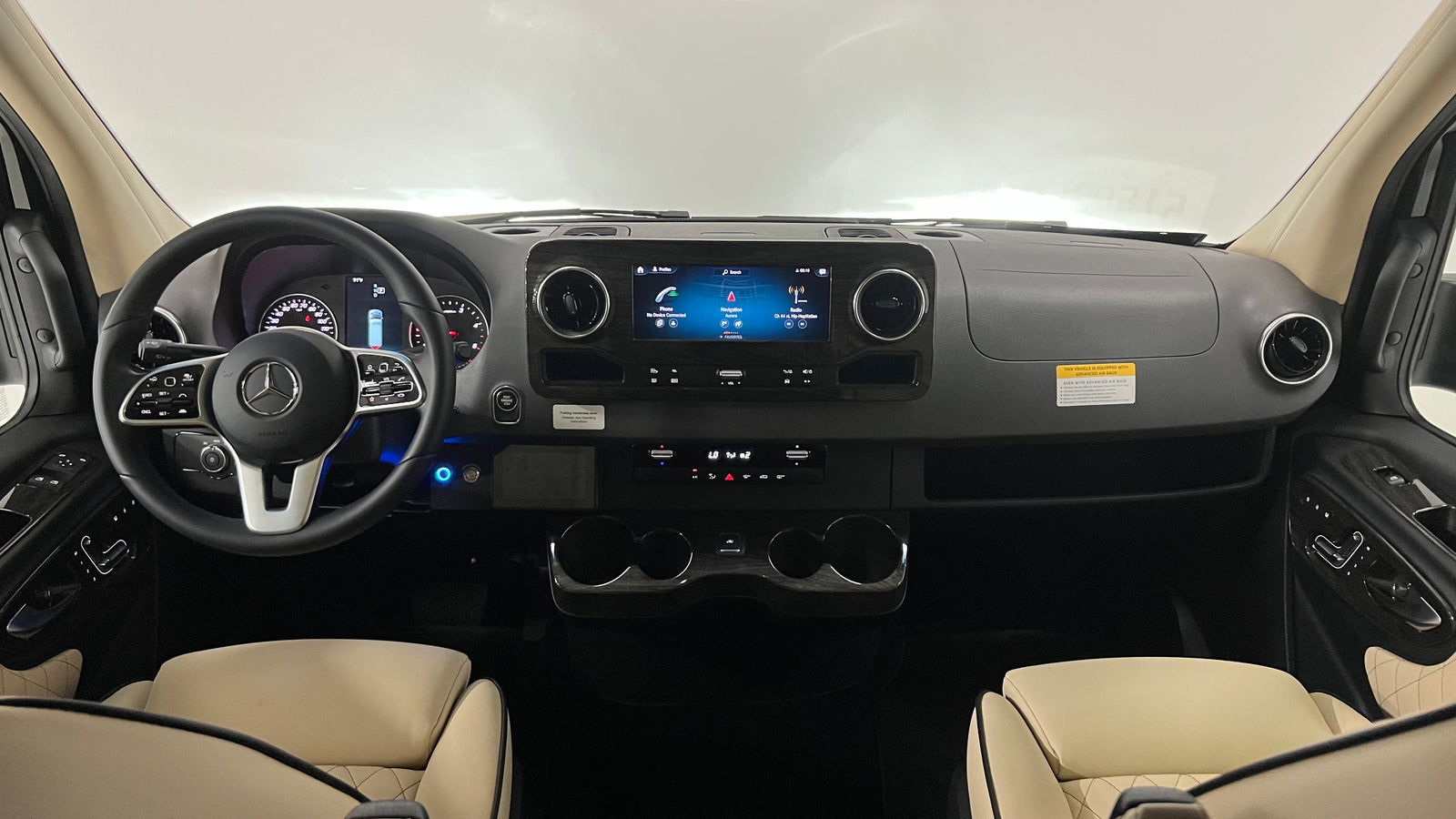 Experience comfort in this Mercedes-Benz RV rental! View of the dashboard, infotainment screen, steering wheel, and cream leather seats.