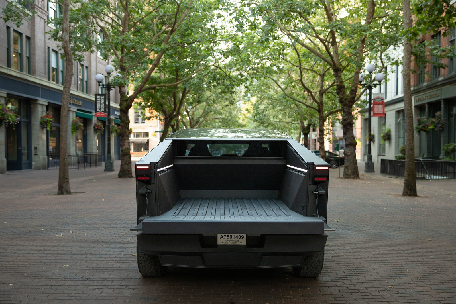 Rear view of a Tesla Cybertruck with open bed, parked on a brick street. A modern EV for travel needs beyond typical rv rental.