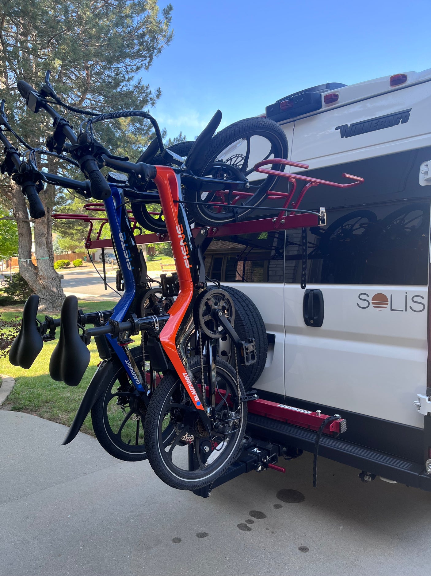 Two folding e-bikes on a hitch-mounted rack at the back of a Winnebago Solis RV, perfect for your next rv rental adventure.