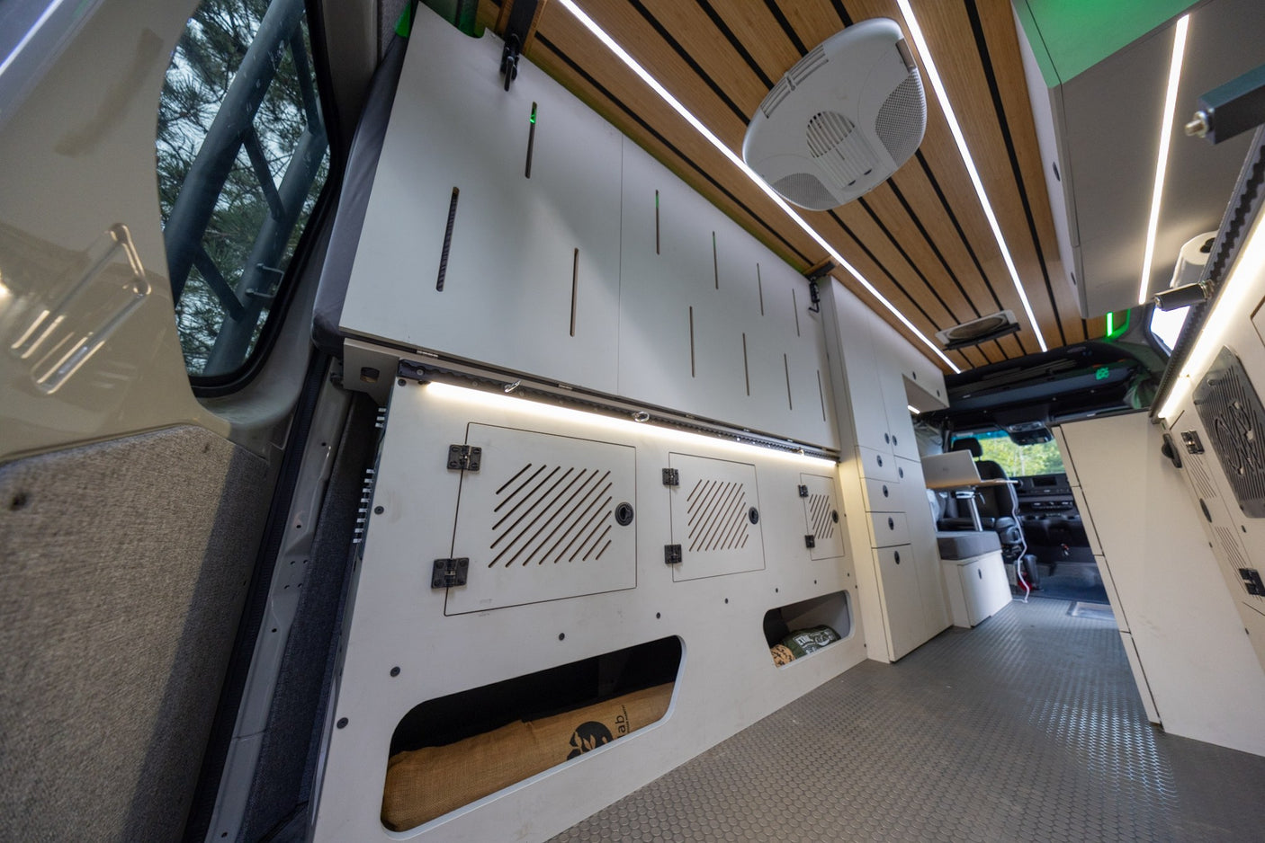 Modern campervan rv rental interior: custom storage, wood-slat ceiling with LED lights, and durable flooring for comfortable travel.