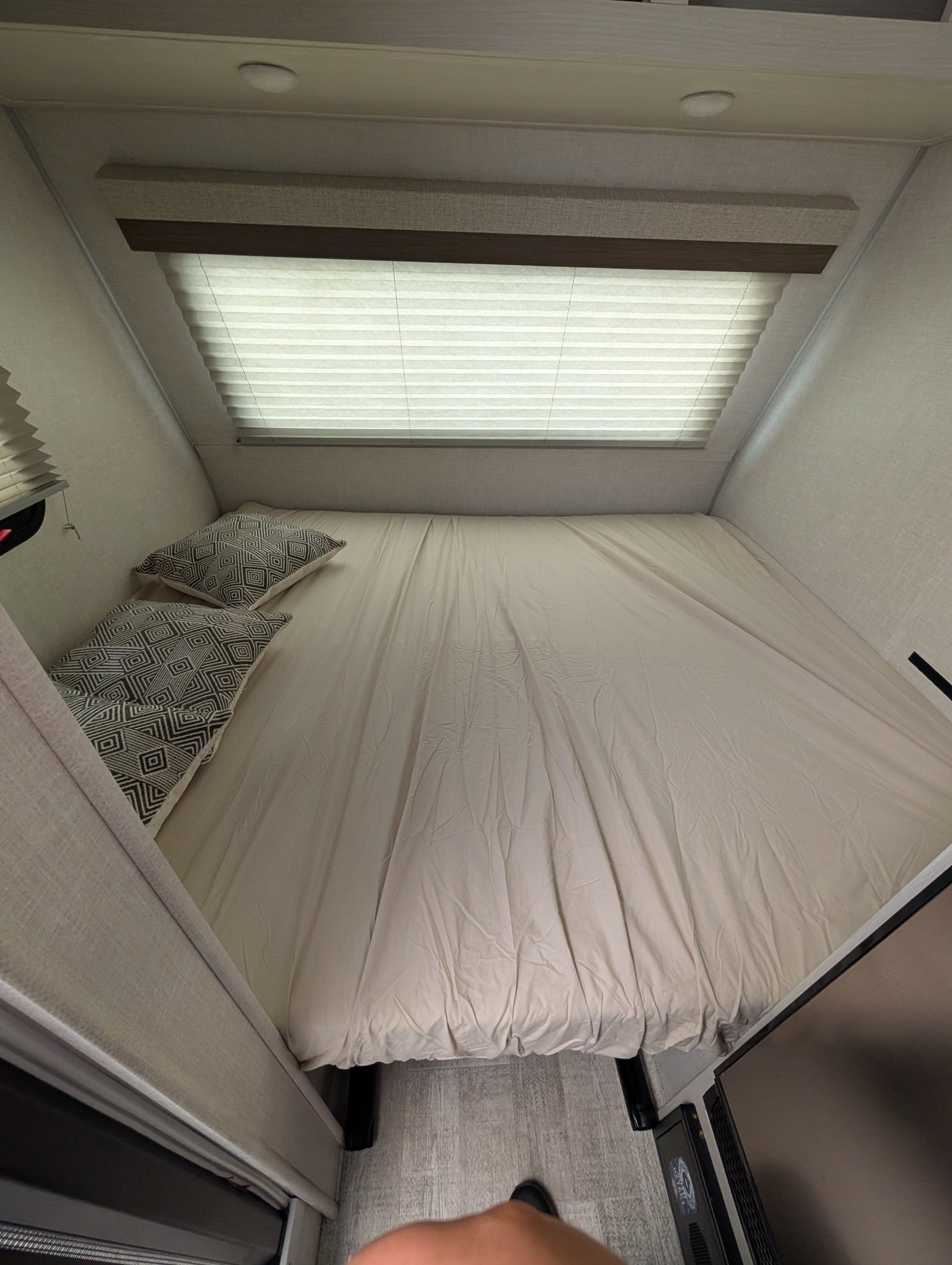 RV rental bedroom: a cozy compact bed with patterned pillows, window blinds, and recessed lighting.