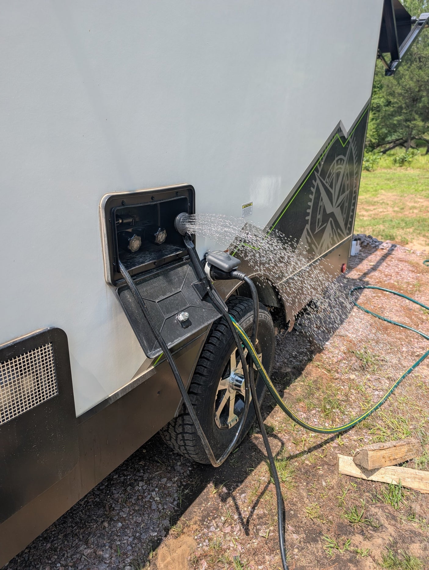 RV rental's outdoor shower spraying water on the side of the trailer, perfect for rinsing off gear and staying clean.