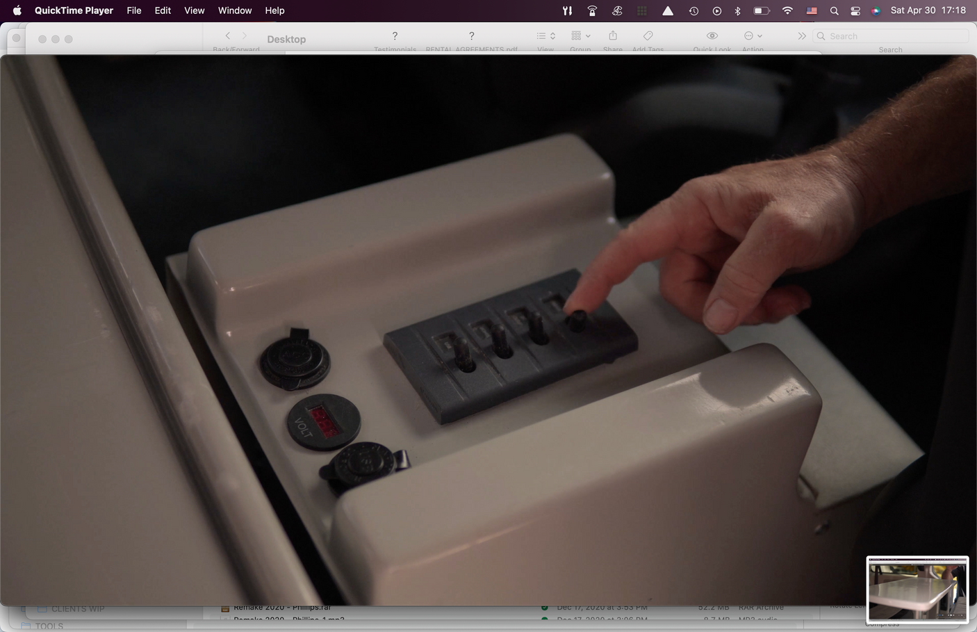 Hand on RV rental control panel, adjusting switches and showing a volt meter. Clear view of interior features.
