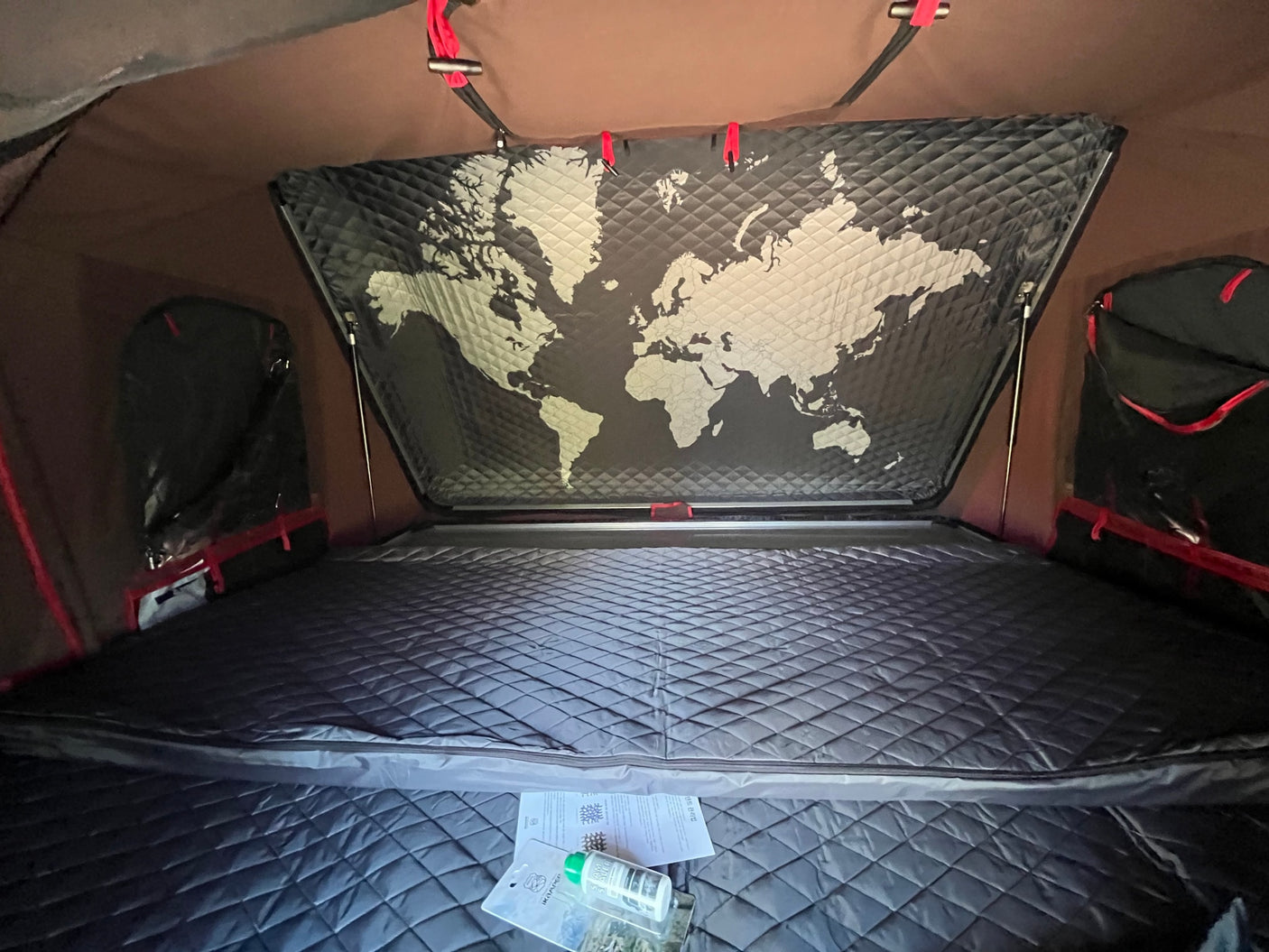 Spacious RV rental interior featuring a cozy quilted bed and a cool world map ceiling, perfect for travel adventures.