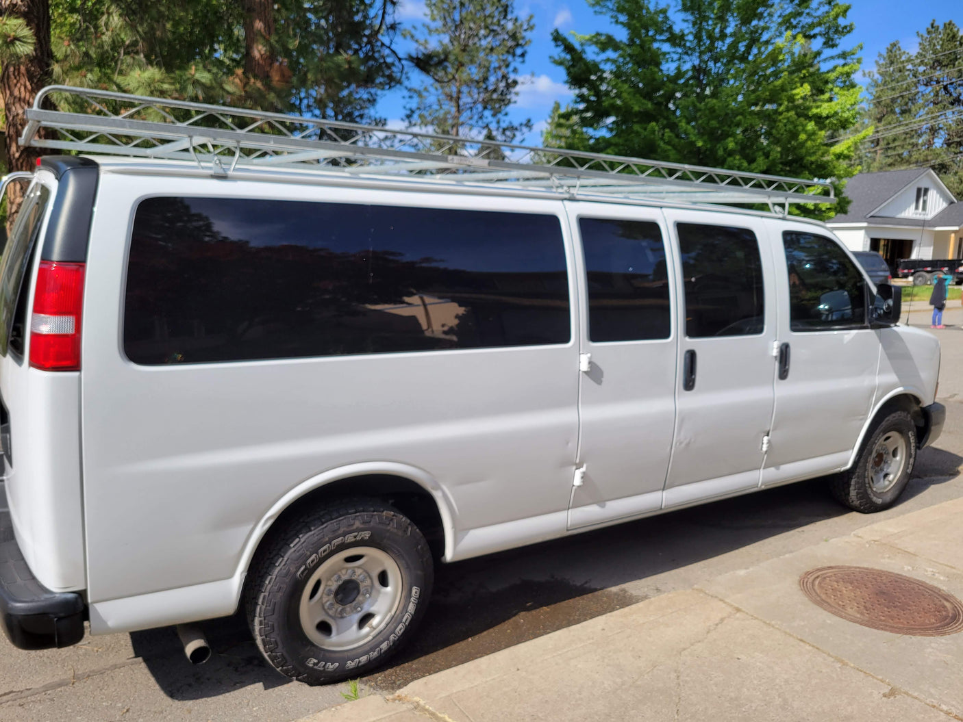White commercial van with a sturdy roof rack, offering ample space for utility or travel, like an RV rental alternative.