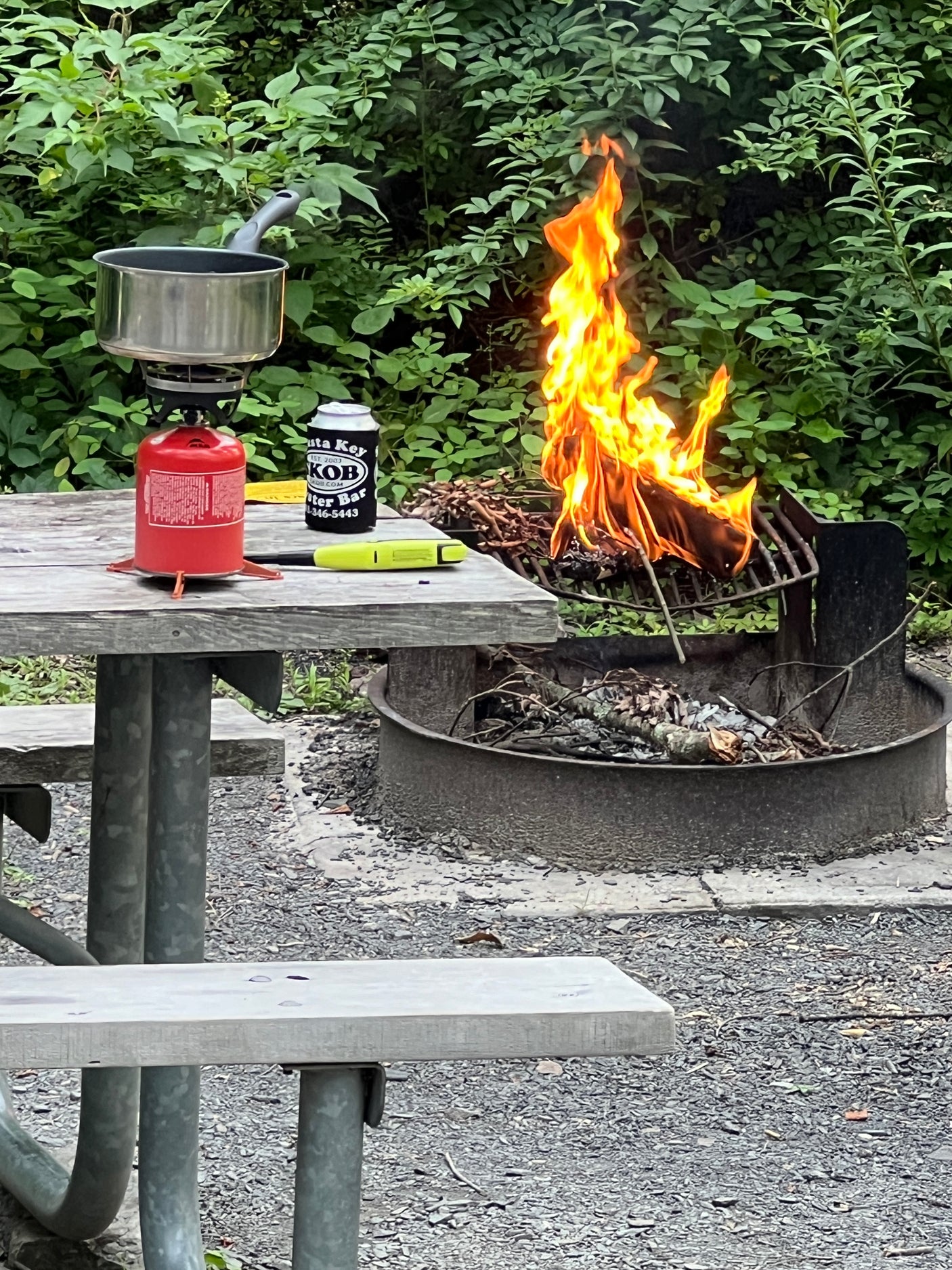 Enjoying a campsite meal prep with a roaring campfire and portable stove. Perfect for your next RV rental adventure!