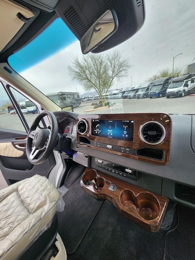 featuring a large bench seat and two side beds. Perfect for comfortable travel.|Inside a modern RV rental: Mercedes Sprinter cockpit with wood trim