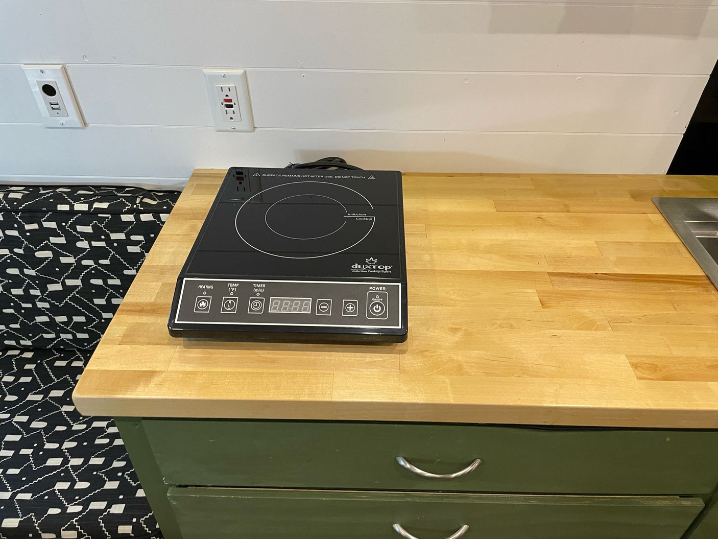 and custom storage. Ideal for family trips.|This RV rental features a compact kitchenette with a Duxtop induction cooktop on a wooden countertop