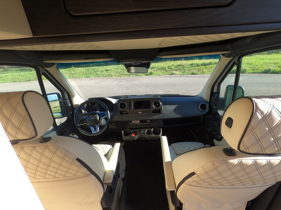 Interior of an rv rental cabin, showcasing luxurious quilted seats, a modern dashboard, and steering wheel.