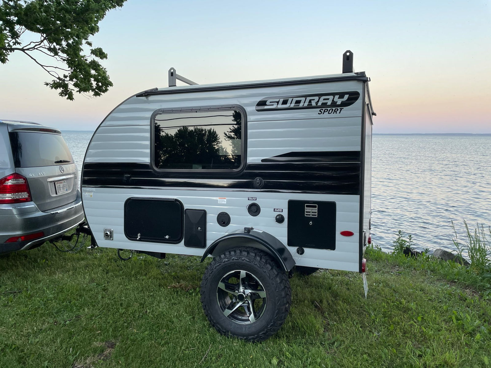 Compact Sundray Sport RV rental parked by a tranquil lake at dusk