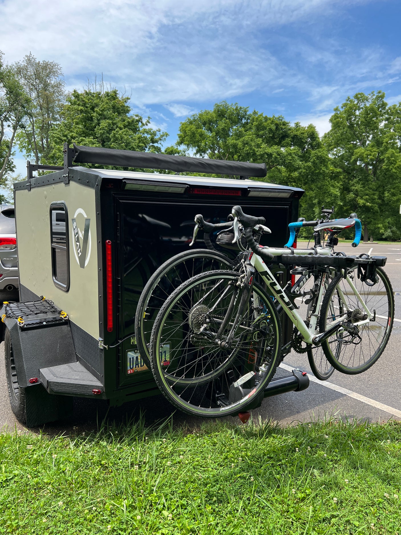 Rugged adventure trailer with two bikes, ready for an RV rental trip. Perfect for outdoor escapes under blue skies.