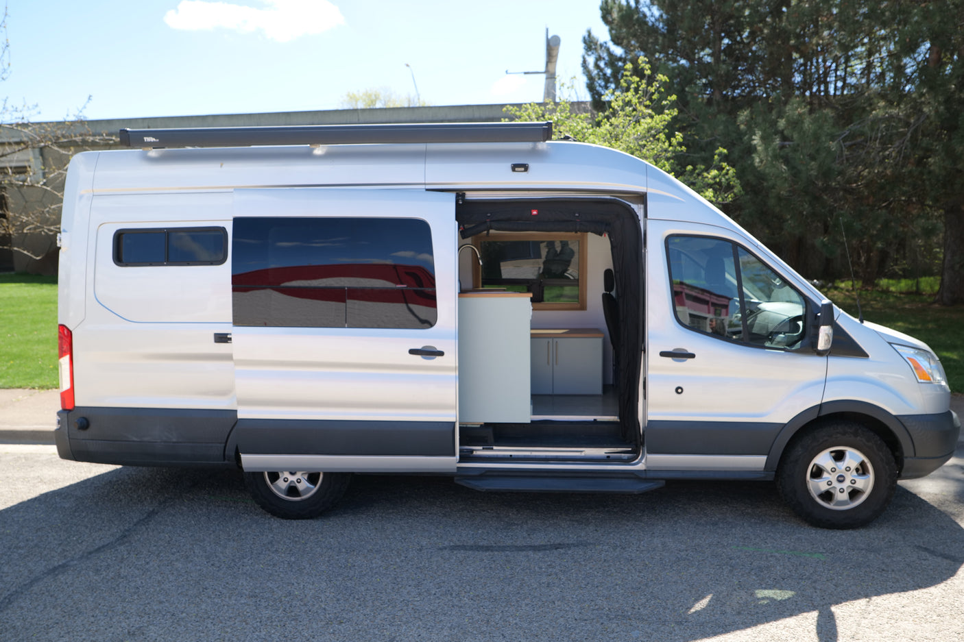 Silver camper van RV rental, side door open, showcasing a modern interior kitchen. Ideal for road trips and adventure.