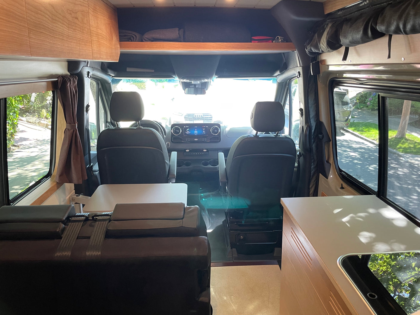 Step inside this RV rental! View of the front cabin, dashboard, and comfortable living area with kitchenette.