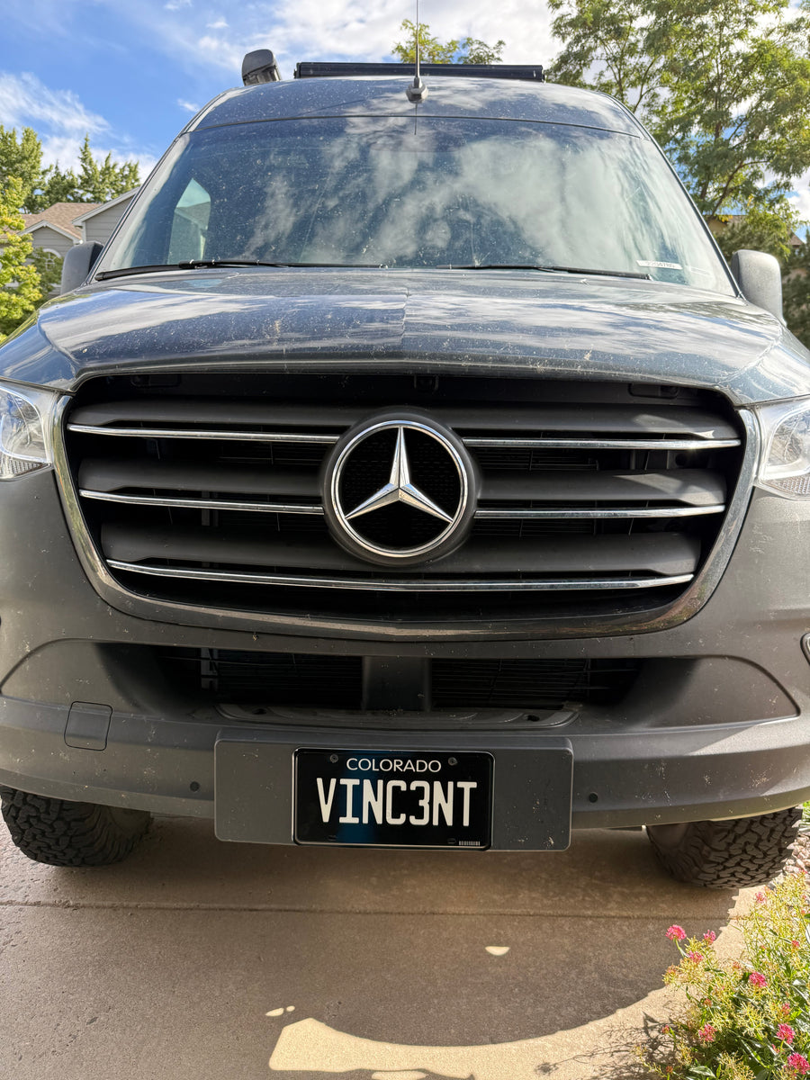 Front view of a dusty, dark Mercedes-Benz Sprinter van, an rv rental, with a Colorado 'VINC3NT' plate.