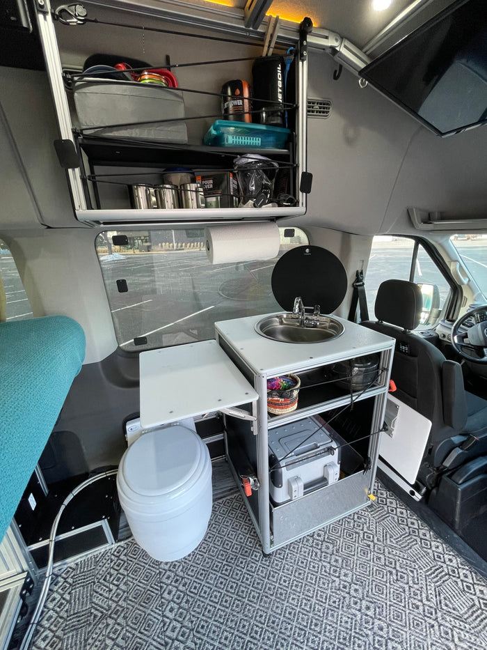 This rv rental showcases a compact camper van's mobile living space: kitchenette, portable toilet, storage, and bed area.