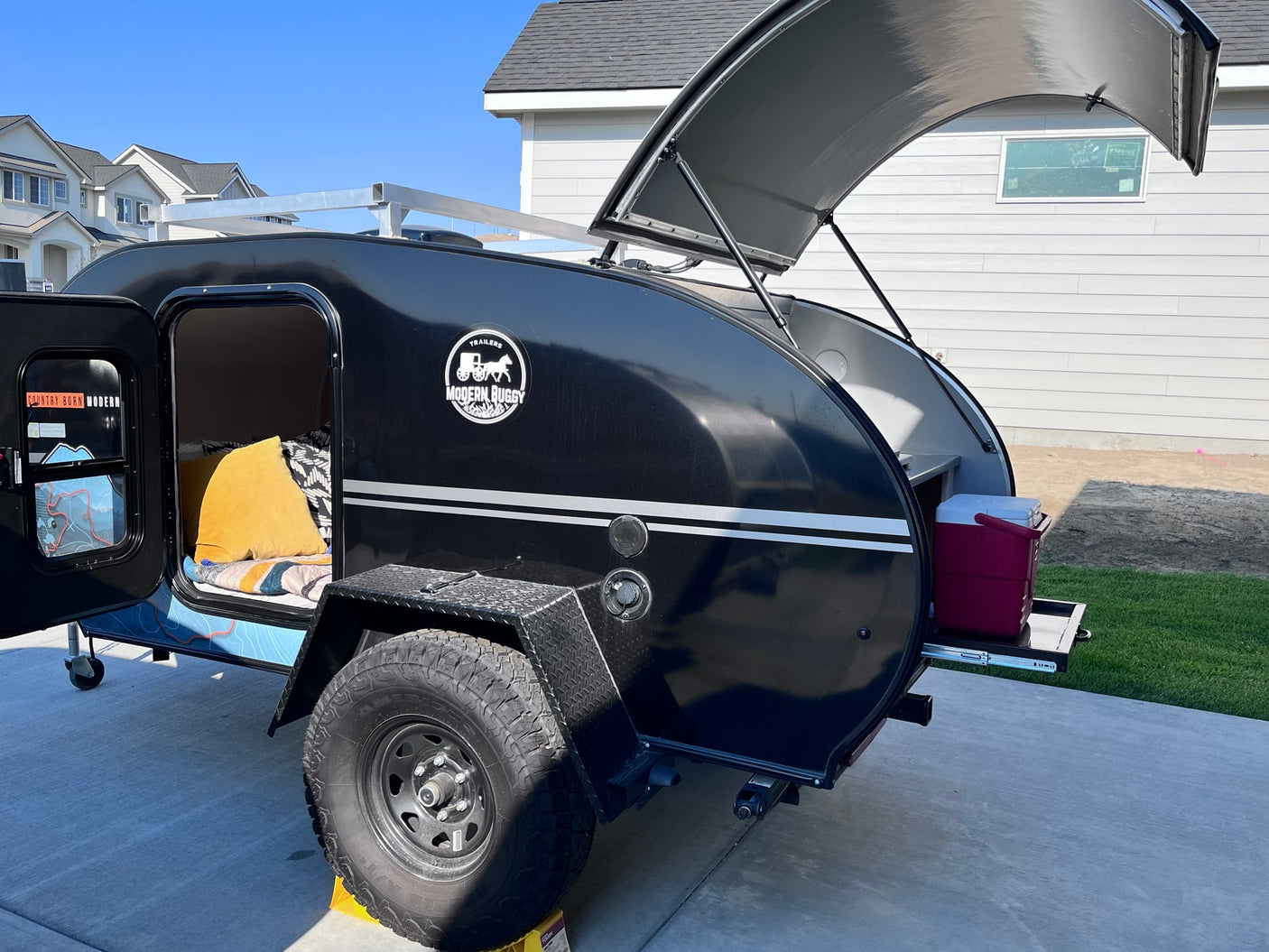 Black Modern Buggy off-road teardrop RV rental showing open sleeping area & galley kitchen.