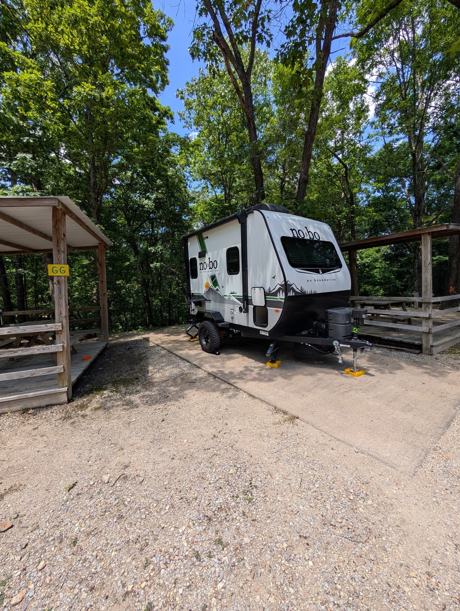 White No Boundaries RV rental at a shaded campsite with a picnic shelter, ready for outdoor adventure.