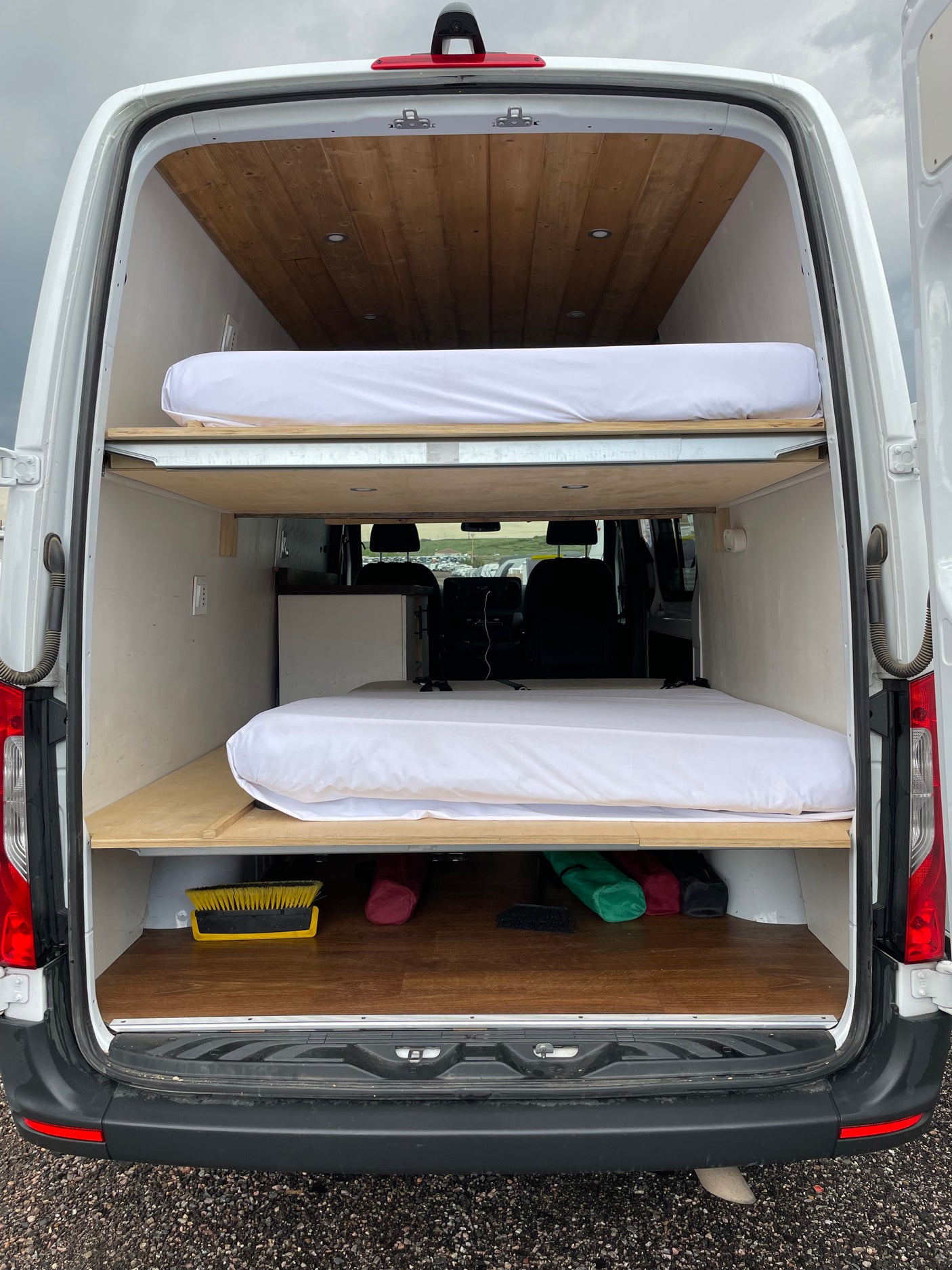 Inside an RV rental: custom camper van with dual bunk beds, wood ceiling, and floor for mobile living.