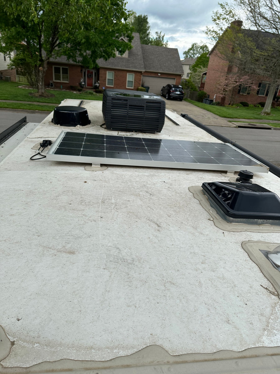 Dirty RV rental roof: solar panel, AC unit, and various vent covers visible.