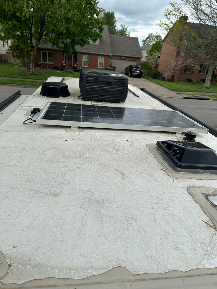 Dirty RV rental roof: solar panel, AC unit, and various vent covers visible.