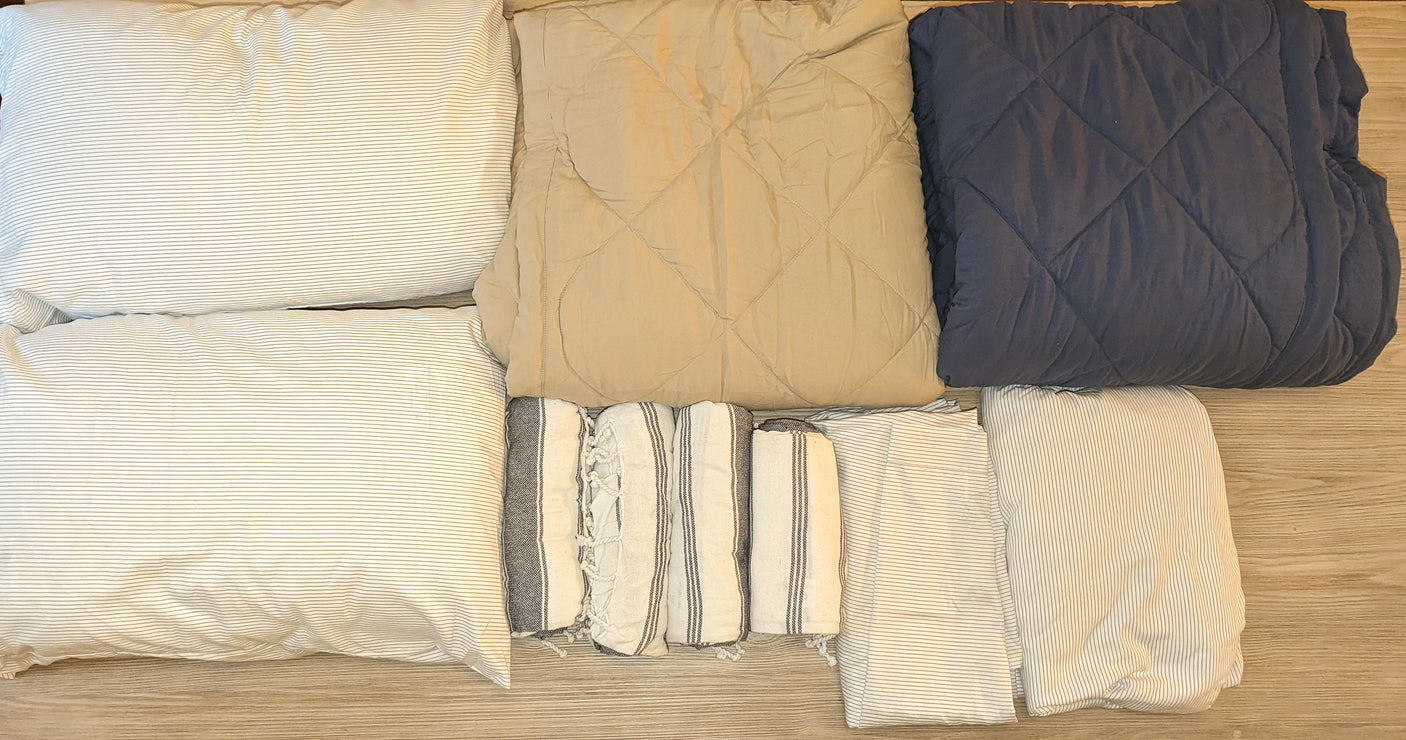 RV rental bedding essentials: neatly folded pillows, comforters, sheets, & towels for a comfortable stay.