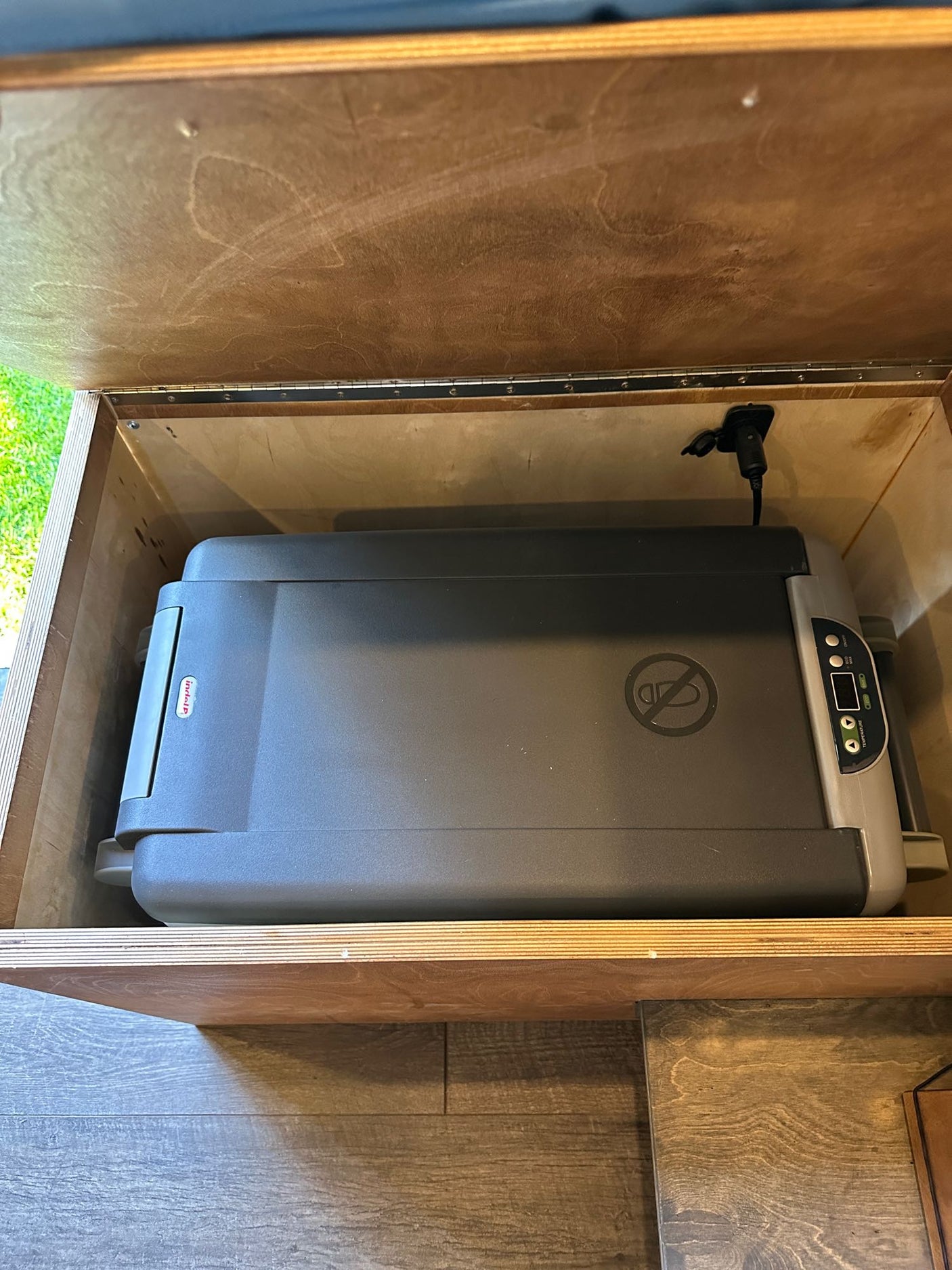 Portable IndelB fridge in a custom wooden cabinet, powered for your RV rental adventures.