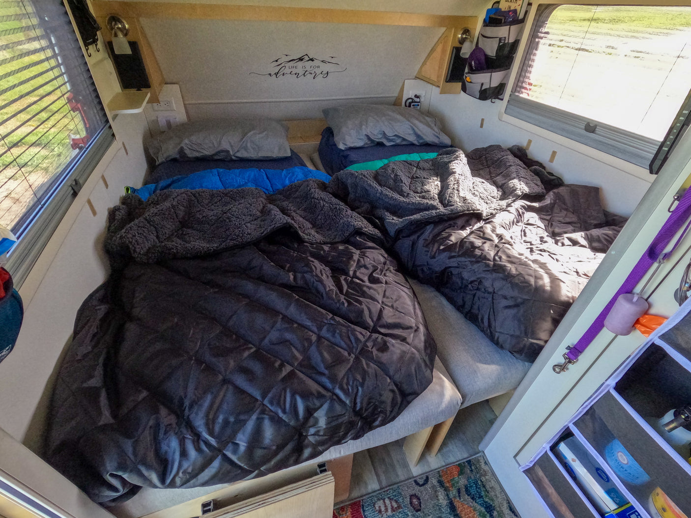 This RV rental offers a cozy sleeping area with two beds, soft blankets, and natural light. Ideal for road trip adventures.