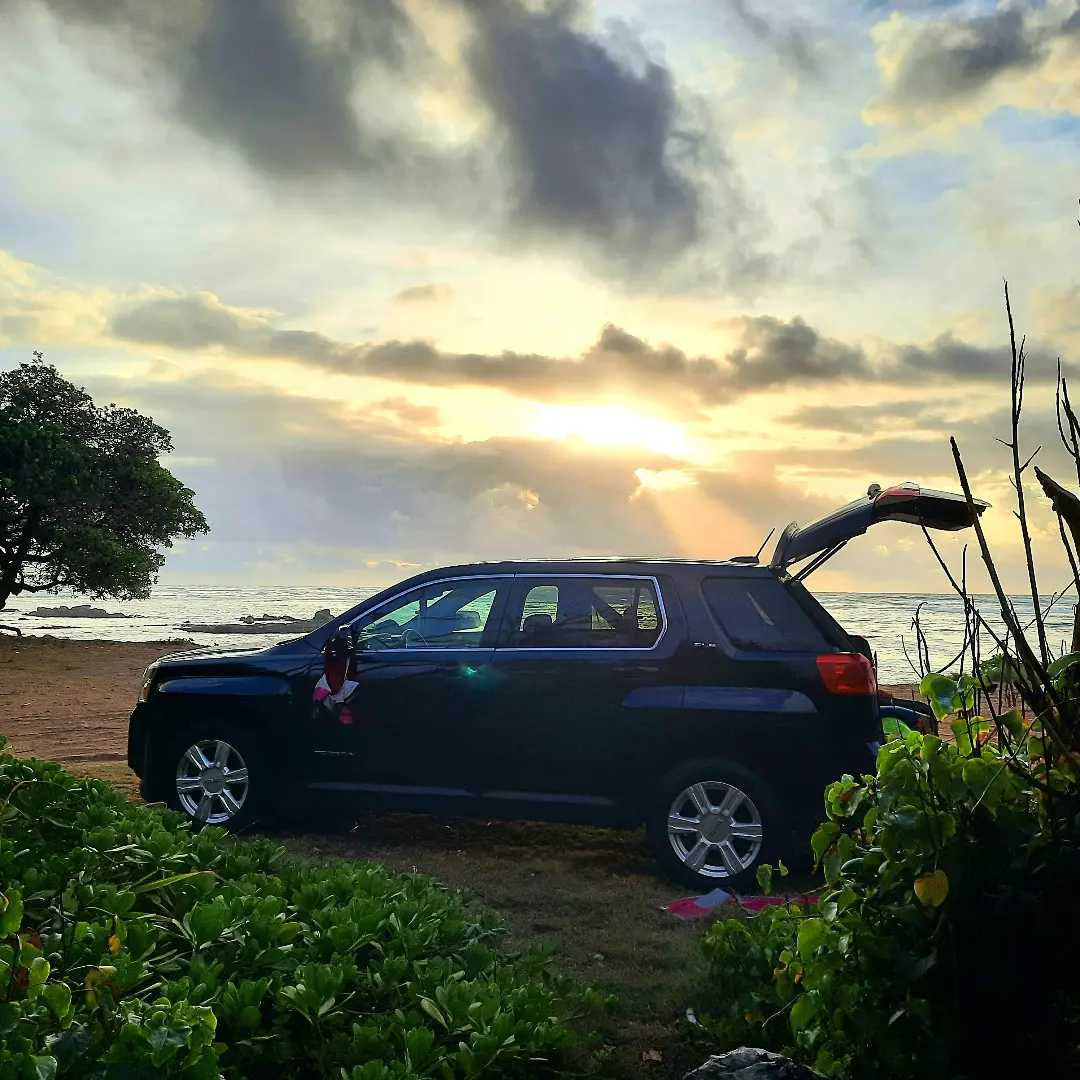 Your next RV rental adventure starts here! Dark SUV parked beachside at sunset, trunk open, ready for travel.