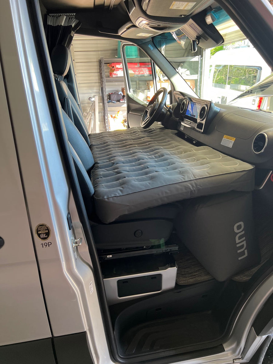 and convenient overhead storage.|Cozy RV rental interior featuring a comfortable bed with white bedding