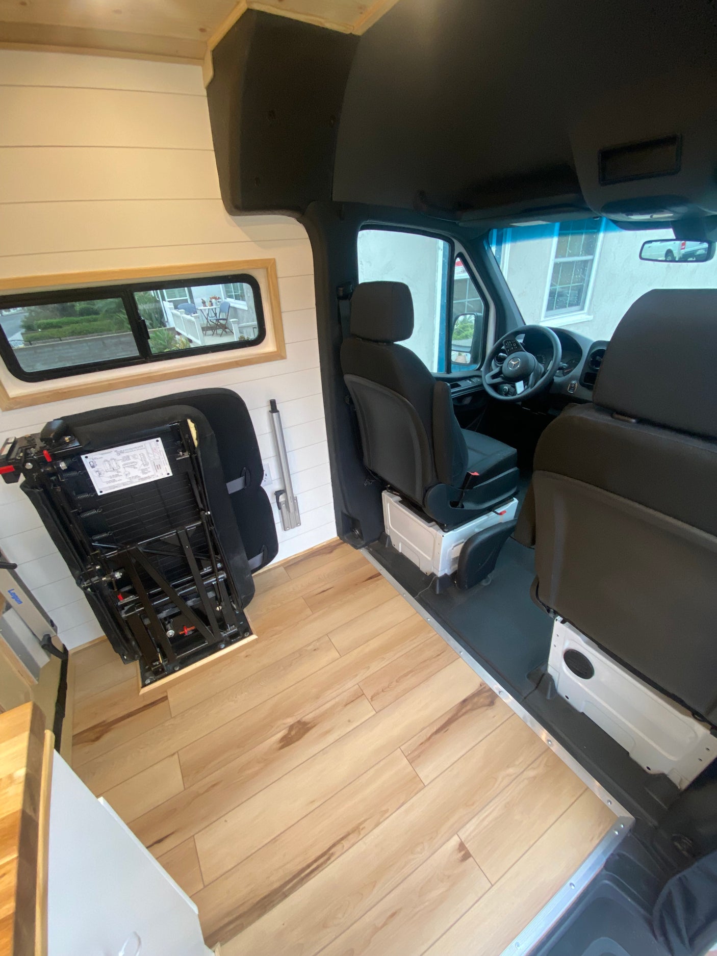 Explore this RV rental's bright interior: front seats, light wood floor, white walls, and side window.