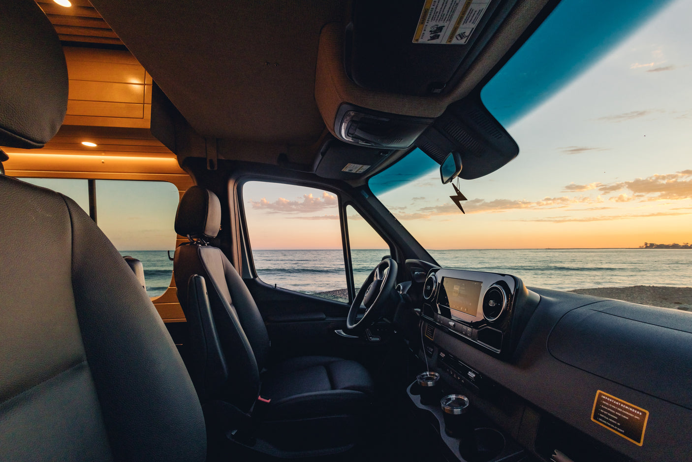 Inside a cozy rv rental, witness a beautiful ocean sunset from the driver's seat. Perfect for travel and relaxation.