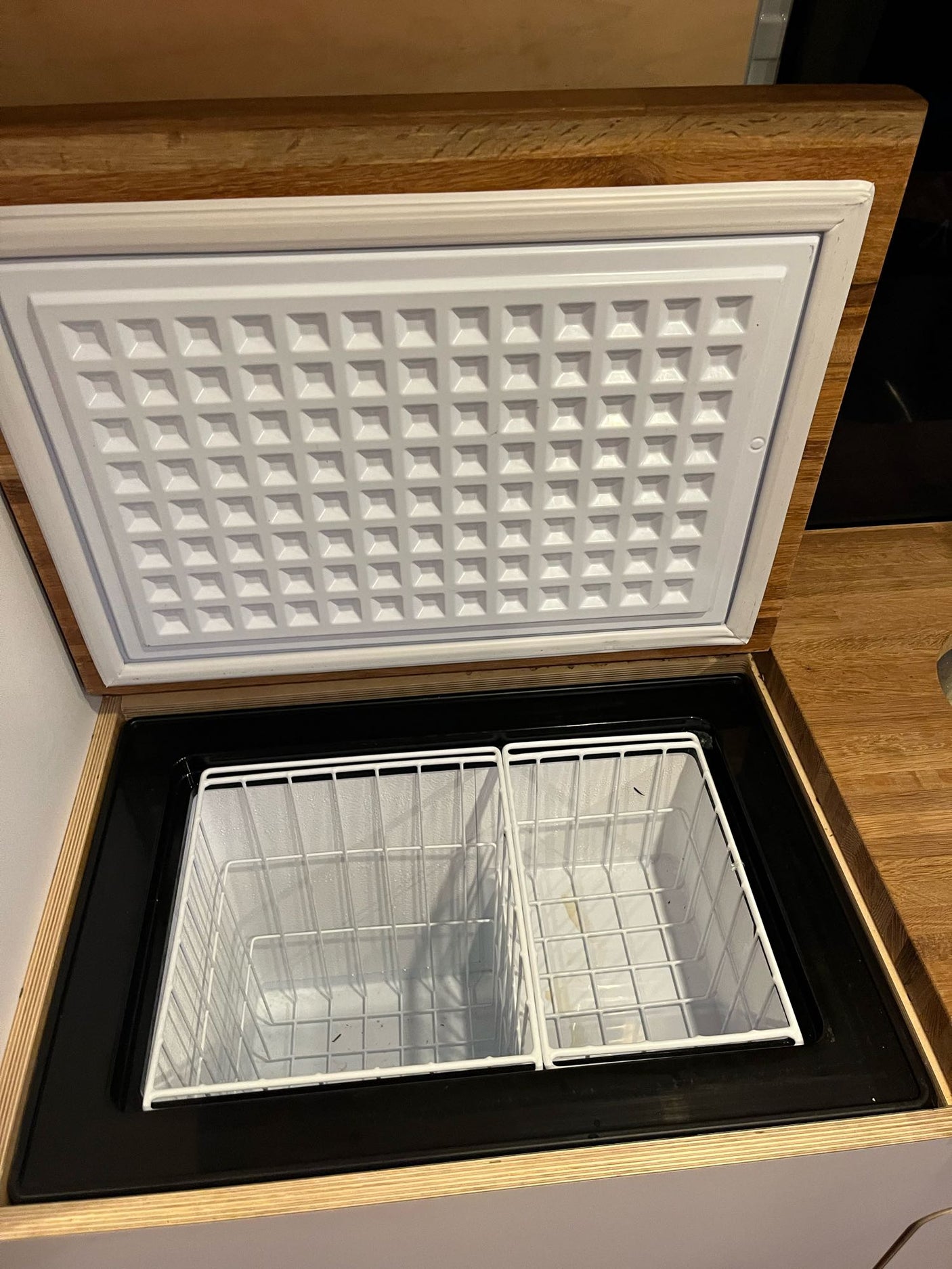 Built-in chest fridge/freezer with wire baskets set in a wood counter, ideal for your RV rental trip.