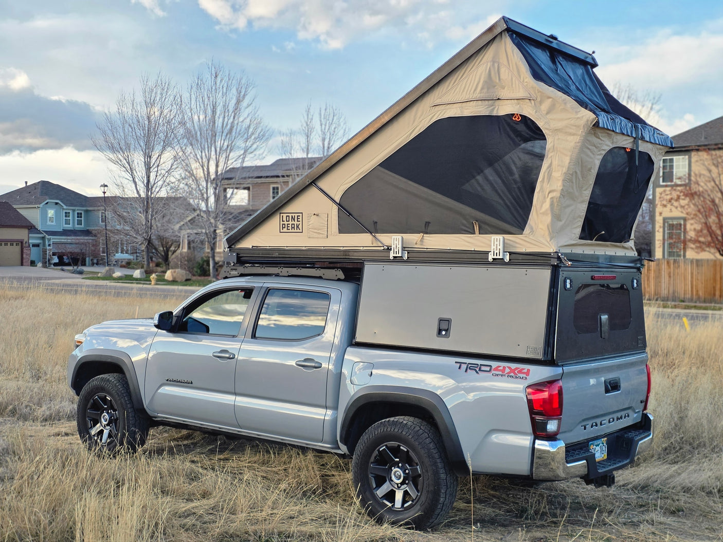 Silver Toyota Tacoma with a Lone Peak pop-up rooftop tent & truck camper. An ideal RV rental for off-grid camping adventures.