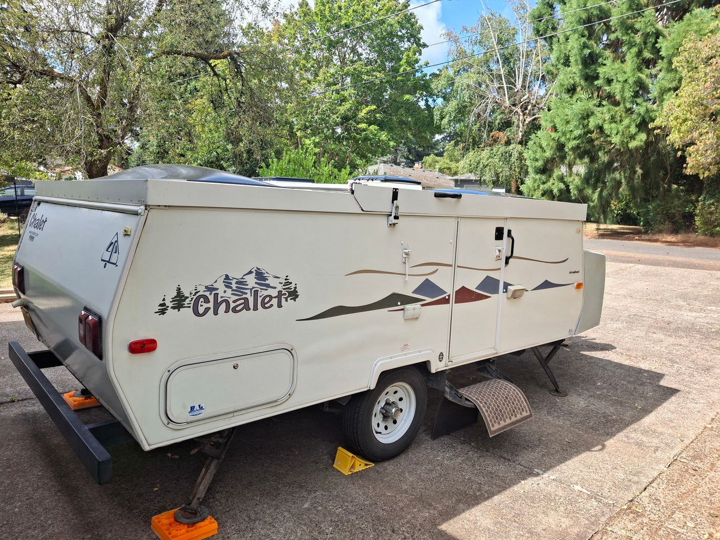 perfect for an RV rental. Parked on concrete with stabilizing jacks and mountain decals.|RV rental floor plan: Couch (52"x76" bed) & dinette (40"x76" bed) conversions