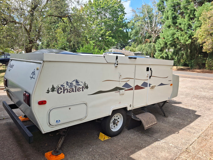 perfect for an RV rental. Parked on concrete with stabilizing jacks and mountain decals.|RV rental floor plan: Couch (52"x76" bed) & dinette (40"x76" bed) conversions