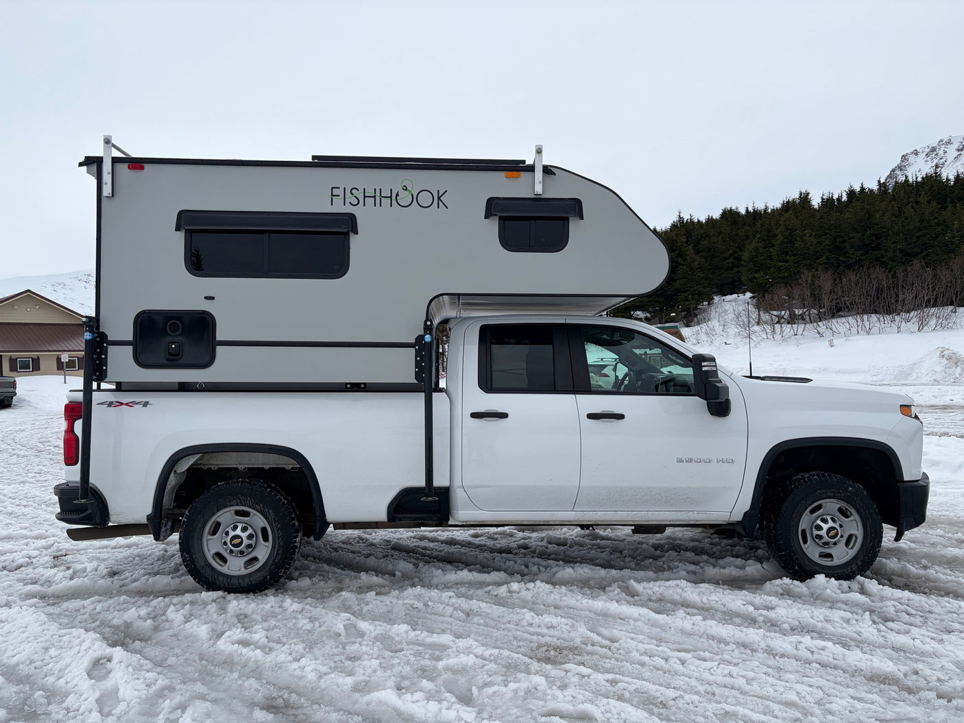 White Chevrolet 2500 HD 4x4 truck with a "FISHHOOK" RV camper