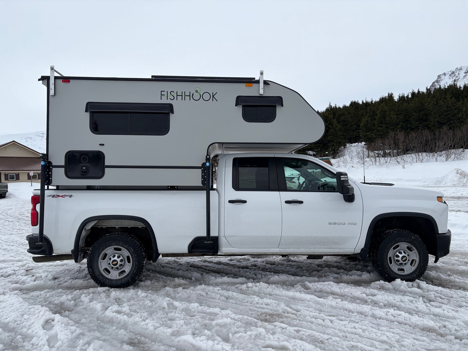White Chevrolet 2500 HD 4x4 truck with a "FISHHOOK" RV camper