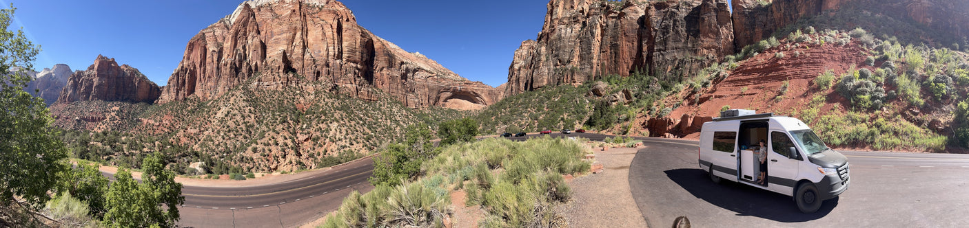 Panoramic view of a scenic mountain road, with an **RV rental** parked to take in the majestic red rock landscape.