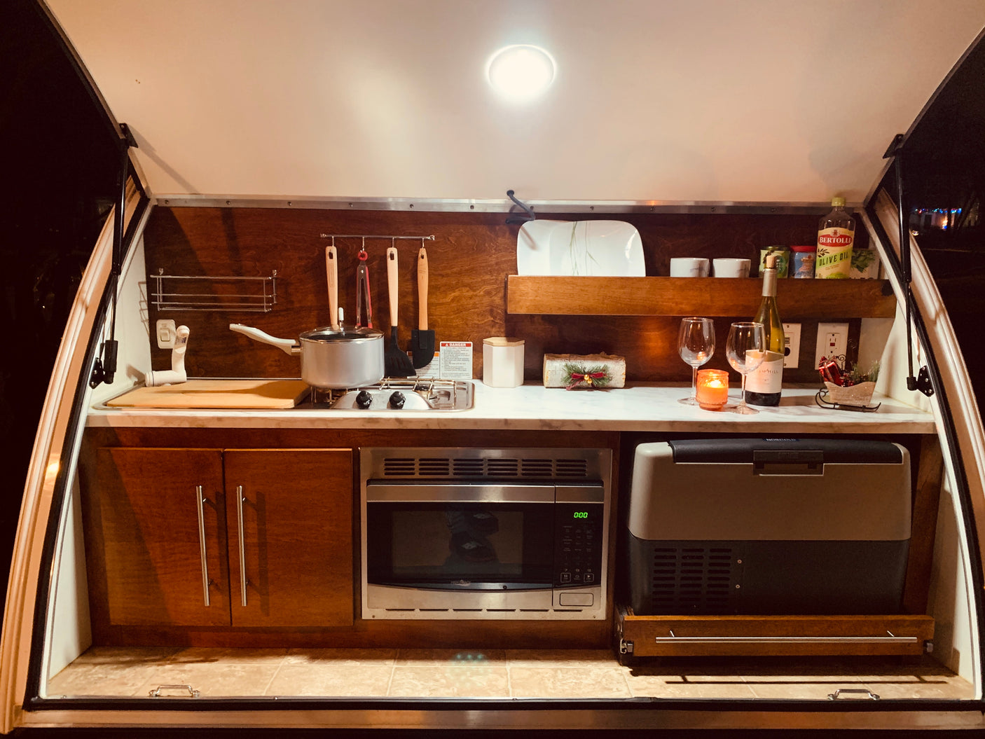 RV rental: Compact camper kitchen with stove, microwave, and cooler. Ready for your adventure!