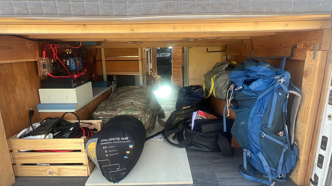 RV rental under-bed storage: visible electrical system, camping gear, and backpacks for adventure.