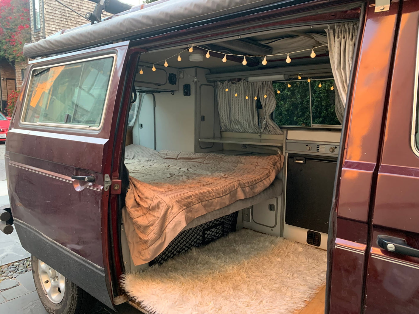 is ready for a desert RV rental adventure.|Dark maroon RV rental van on a white sand path