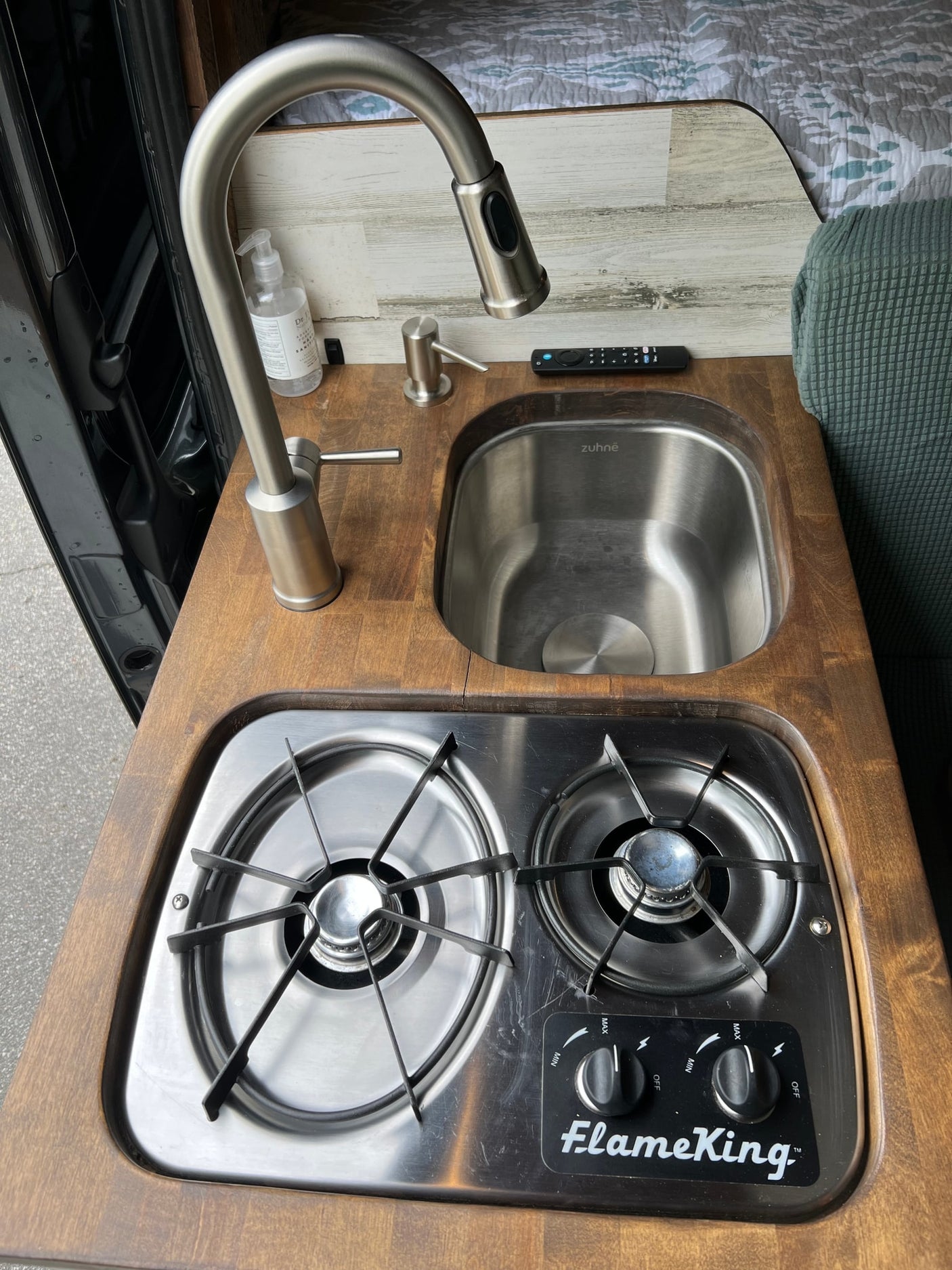 RV rental kitchen: ZUHNE sink with pull-down faucet & FlameKing 2-burner cooktop on wooden counter.